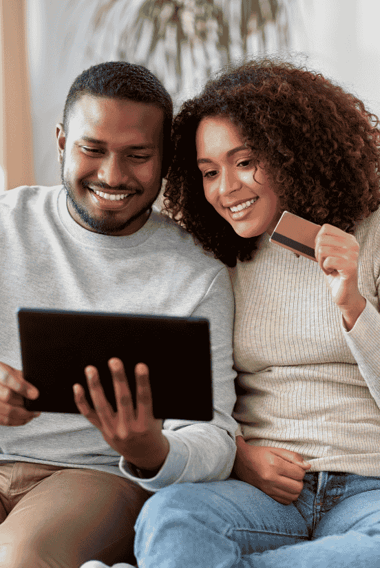 A happy couple shopping online with a tablet and credit card in hand.