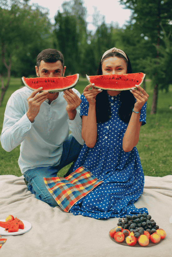 Happy couple having a playful picnic outdoors.