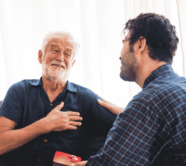 Man presenting a ring box to an older father, seeking approval to propose.