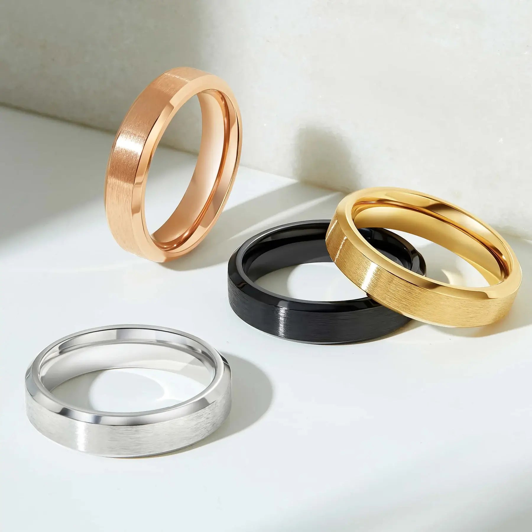 Minimalist brushed wedding bands in rose gold, yellow gold, black, and silver.