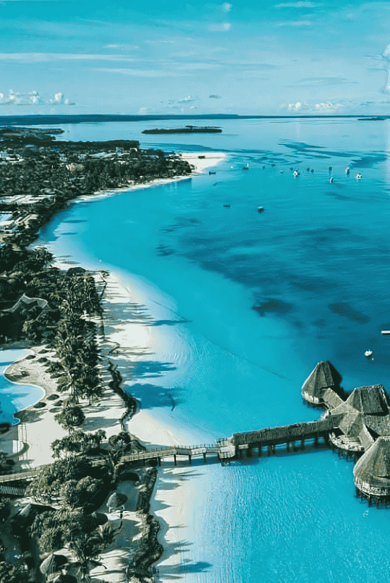 Stunning aerial view of a tropical island with overwater bungalows and blue waters.